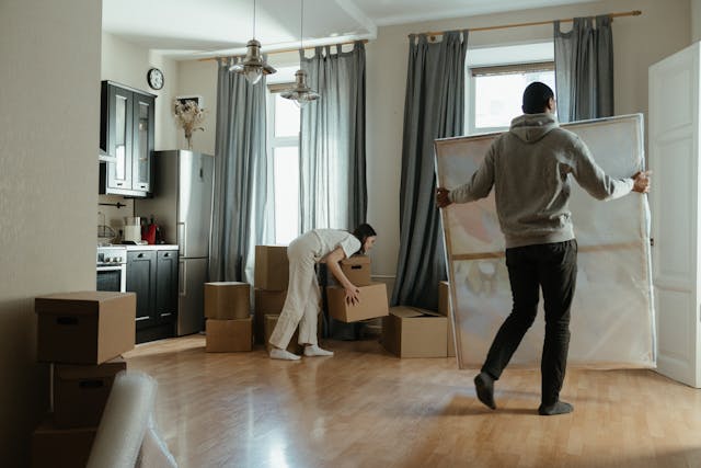 two people moving painting and boxes into their new home