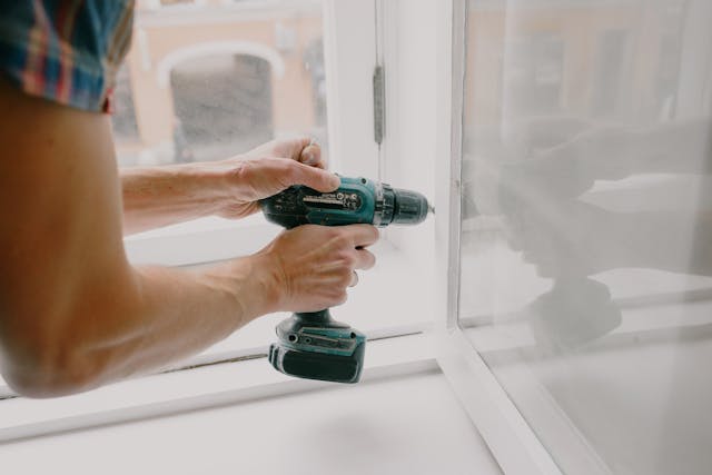 Person using a drill to fix a window hinge