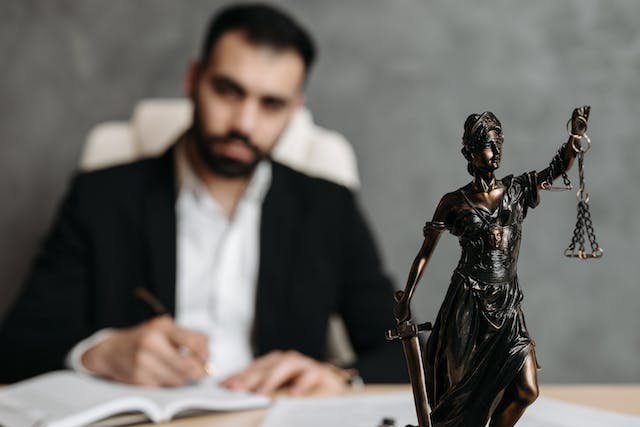 a statue of lady justice with a lawyer in the background