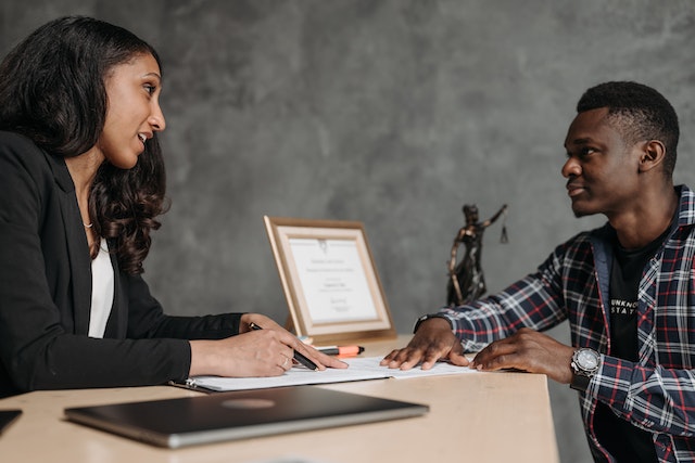 lawyer speaking with a person in a plaid shirt as they look over contracts