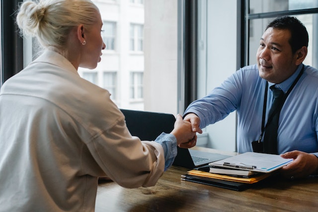 landlord and tenant shaking hands across a desk after signing a new lease contract