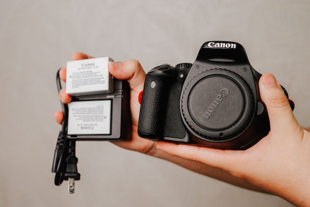 person holding a camera, batteries and SD cards