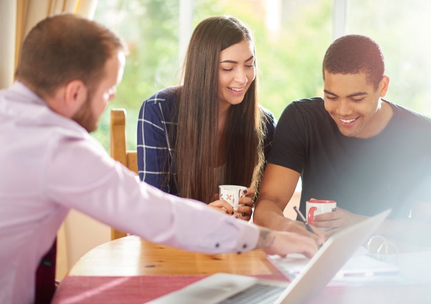 property manager looking over a contract with two tenants as they all sit at a wooden table